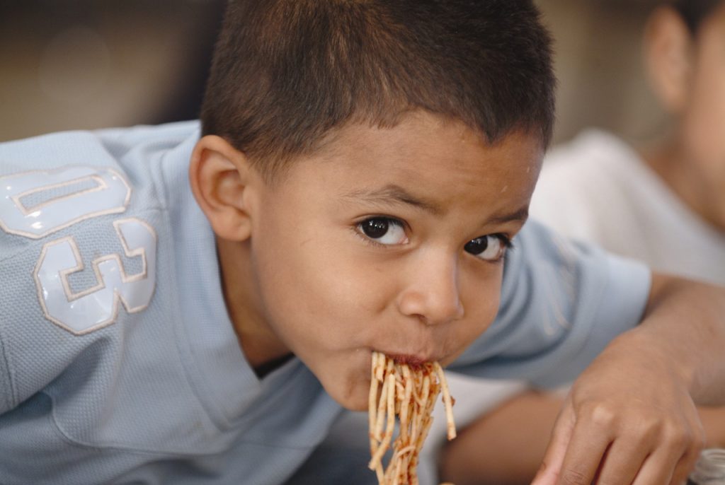 Young boy eats spaghetti