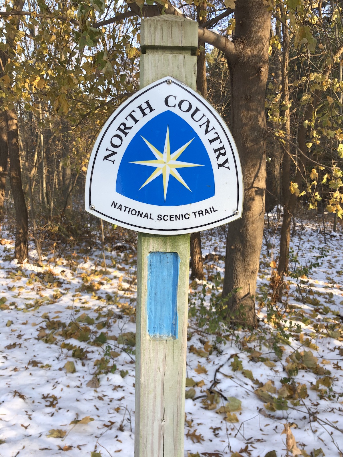 A blue and white sign identifying the North Country Trail