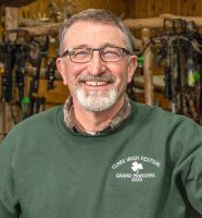 Smiling gentleman with graying hair and trimmed beard in green shirt